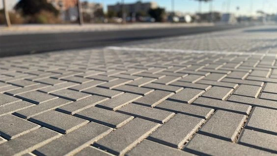 Permukaan paving solo raya motif bata berwarna abu-abu pada area pedestrian dengan susunan pola rapi.