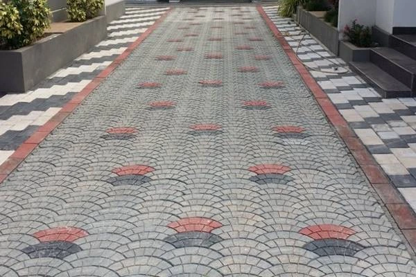 Kombinasi paving block pola fan motif kipas dengan aksen warna merah dan hitam di area halaman rumah