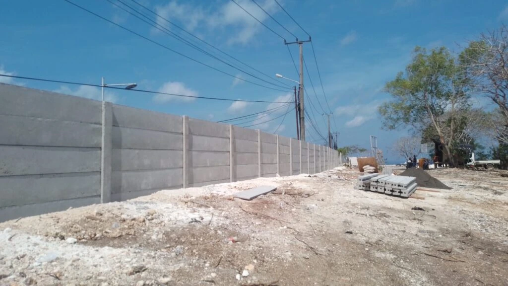 Pagar panel beton terpasang di area proyek konstruksi dengan tiang beton dan susunan panel yang rapi