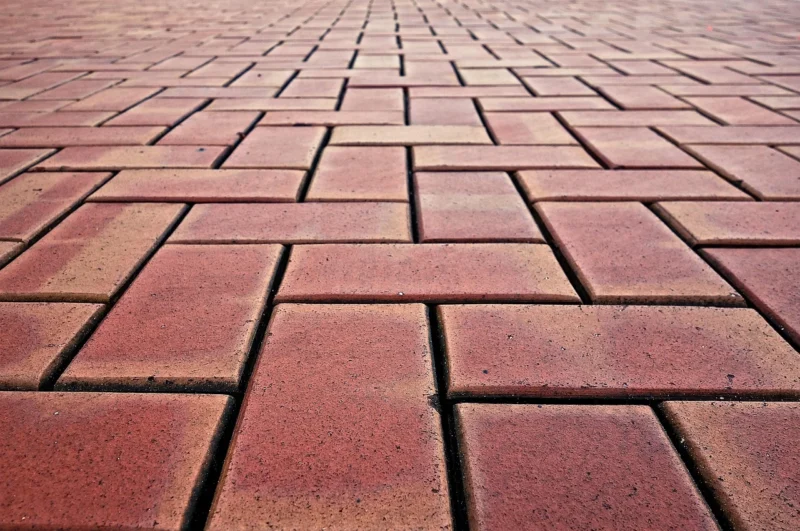 Permukaan paving block merah tersusun rapi dengan pola bata