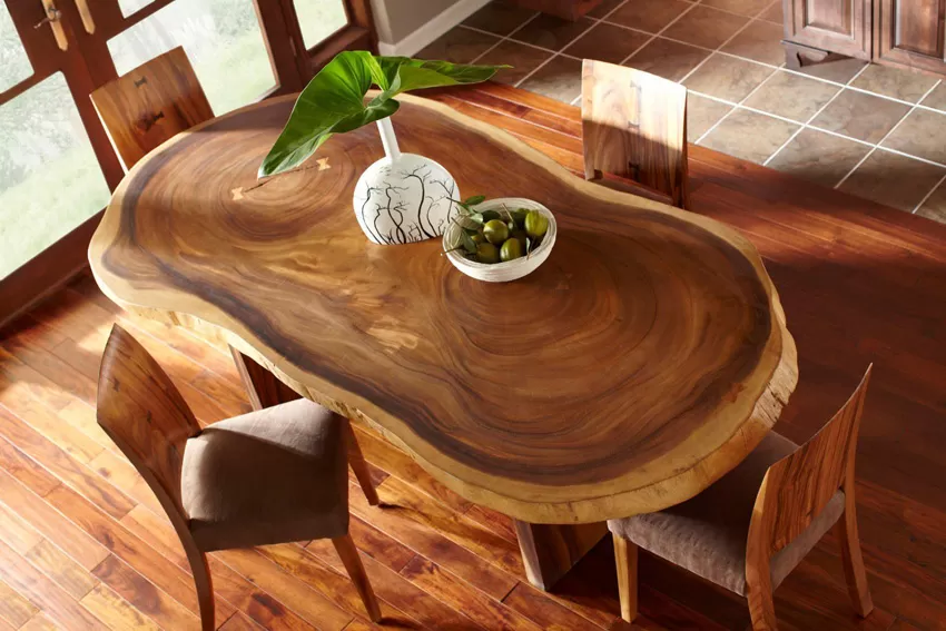 Meja makan mebel kayu slab alami dengan pola serat indah, dilengkapi kursi kayu dan dekorasi vas di ruang interior rumah.