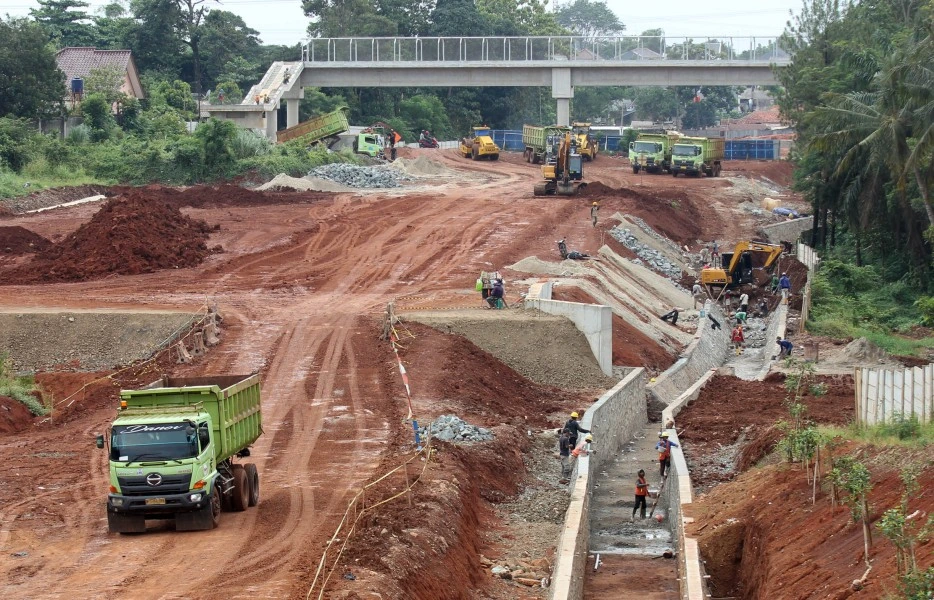 Pekerjaan konstruksi proyek jalan tol di Jawa Tengah dengan alat berat, truk material, dan saluran drainase beton pracetak