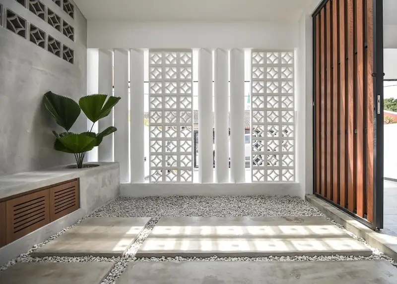 Loster dinding beton motif geometris sebagai ventilasi dan pencahayaan alami pada koridor rumah modern